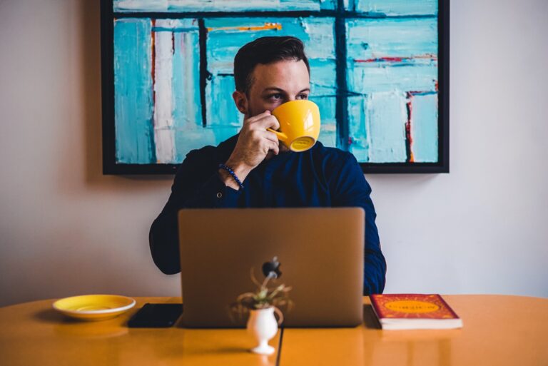 blog writer traits a man sitting in front of a laptop while drinking coffee